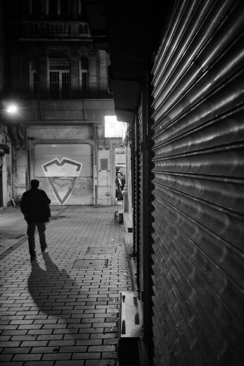 Free Silhouette of a person walking down a dimly lit urban alley at night. Stock Photo