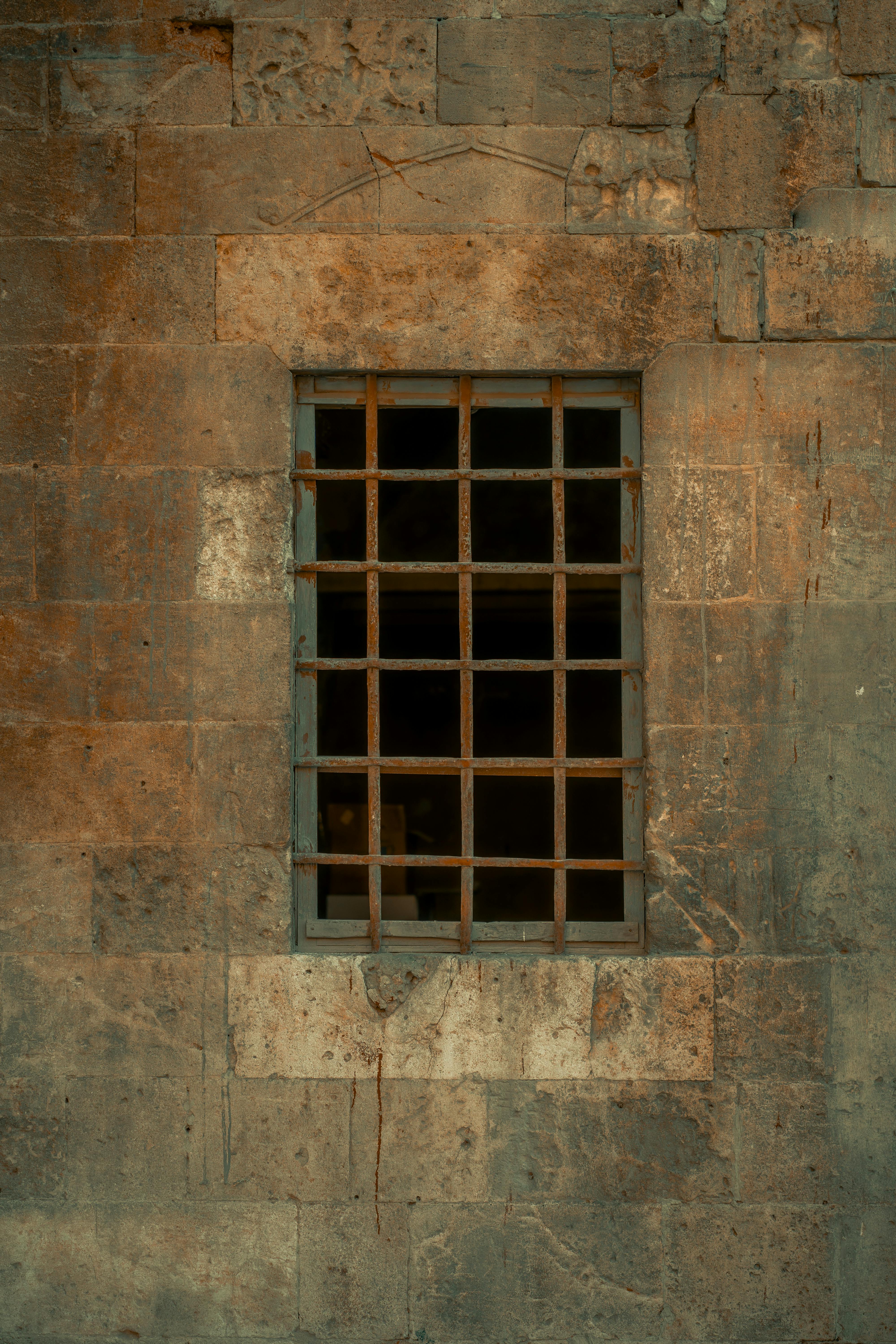 gratis Een rustiek raam met ijzeren tralies in een oude stenen muur, dat doet denken aan historische architectuur. Stockfoto