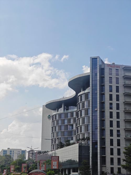 Free Contemporary high-rise building with unique architecture in an urban setting under a clear blue sky. Stock Photo