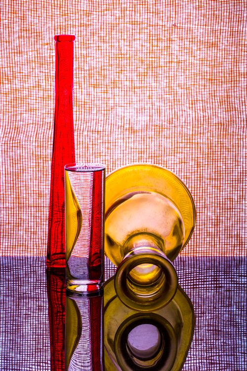 Free Artistic still life photo featuring red and yellow glass bottles with reflections. Stock Photo