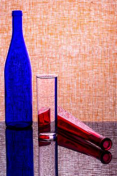 Artistic arrangement of colorful glass bottles against a patterned background with reflections.