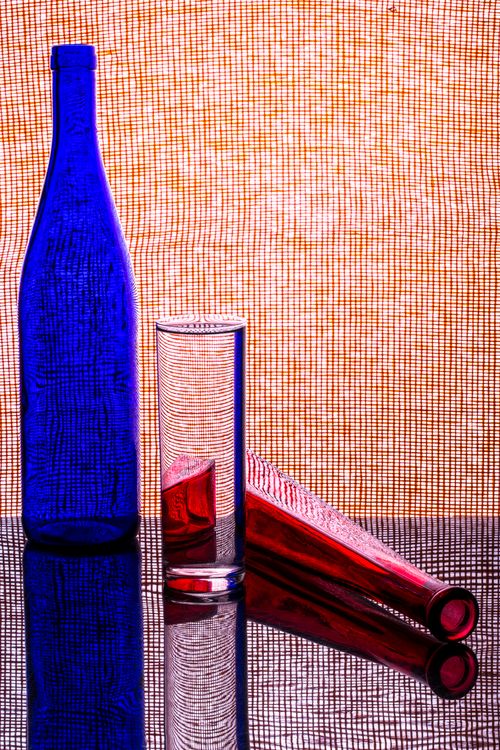 Free Artistic arrangement of colorful glass bottles against a patterned background with reflections. Stock Photo