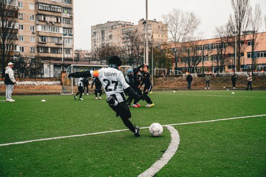 Kids playing soccer on an urban field in Kyiv, showcasing teamwork and sportsmanship.