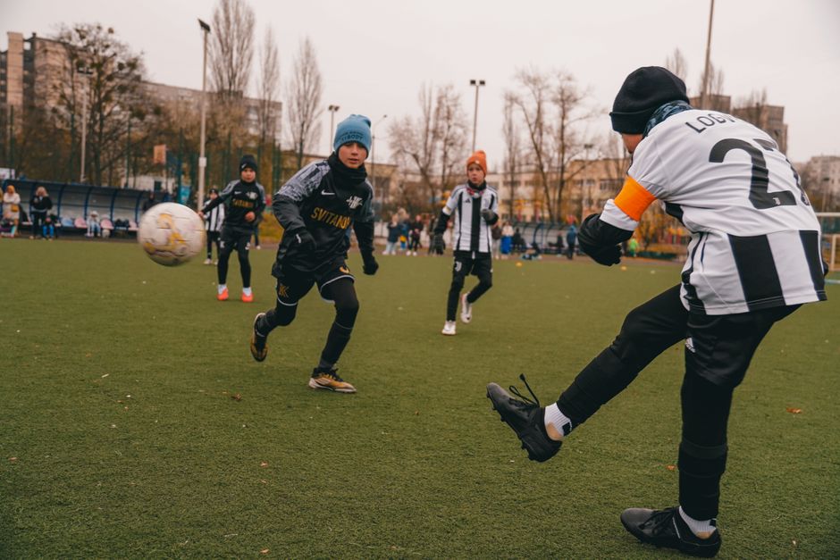 A lively youth soccer match on a grass field in Kyiv, Ukraine during a cool day.