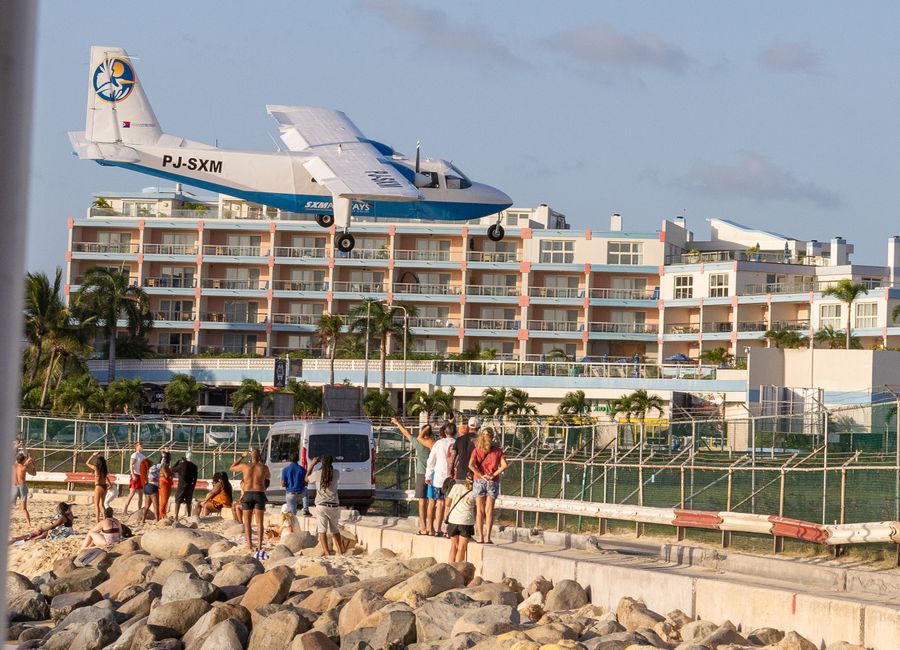 A plane flies low over tourists at Maho Beach, Sint Maarten, near the airport.