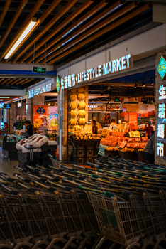 Vibrant indoor lifestyle market featuring carts, fresh fruits, and bakery items under warm lighting.