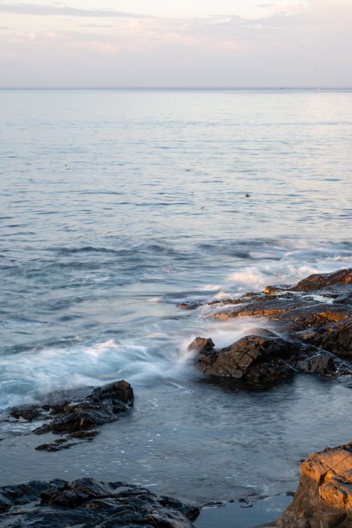 Free Peaceful ocean waves lapping rocky shore in Cape Town at sunset, creating a serene coastal view. Stock Photo