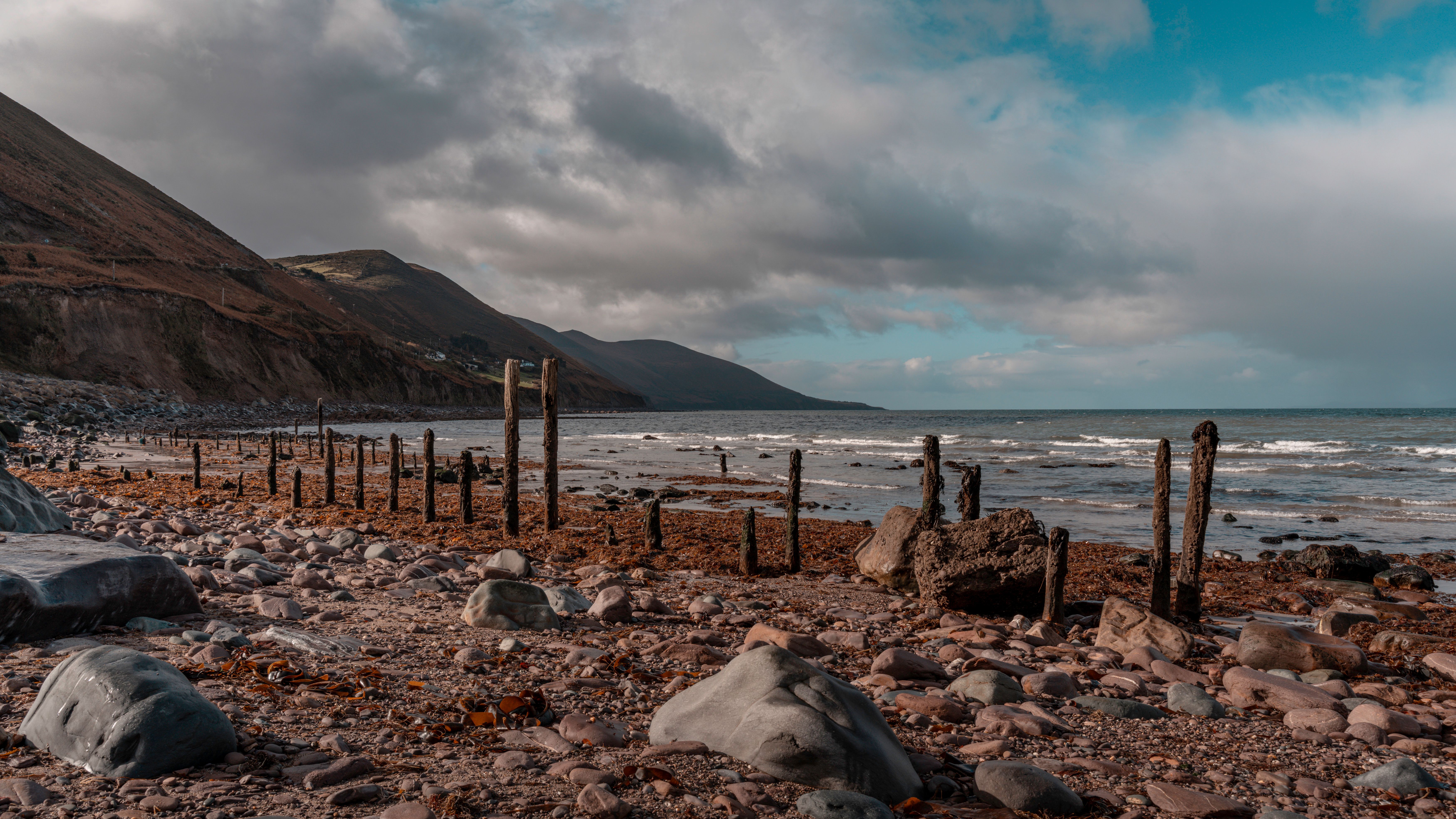 Explore the rugged beauty of an Irish coast with mountains and a rocky shoreline under a cloudy sky.