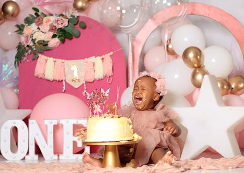 A joyful baby celebrates their first birthday with balloons and cake.