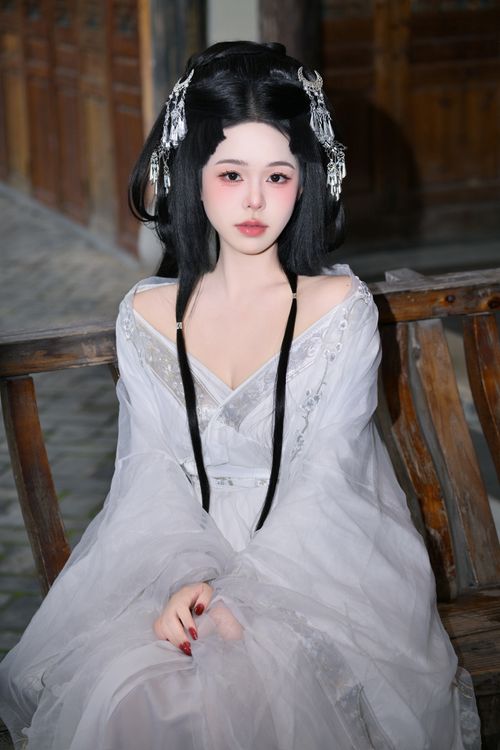 Free Woman in traditional Chinese attire with ornate hair accessories, sitting on a bench. Stock Photo