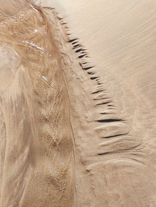 Free An artistic close-up of sand and water patterns on a beach, captured in Casablanca, Morocco. Stock Photo