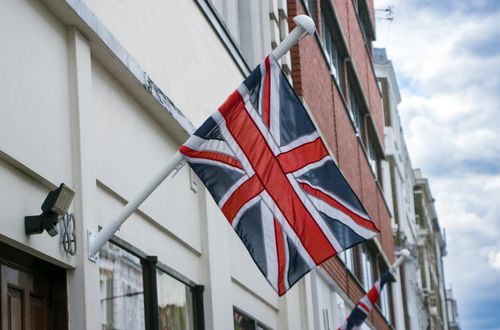 Free Union Jack flag mounted on a building in London street, England. Stock Photo