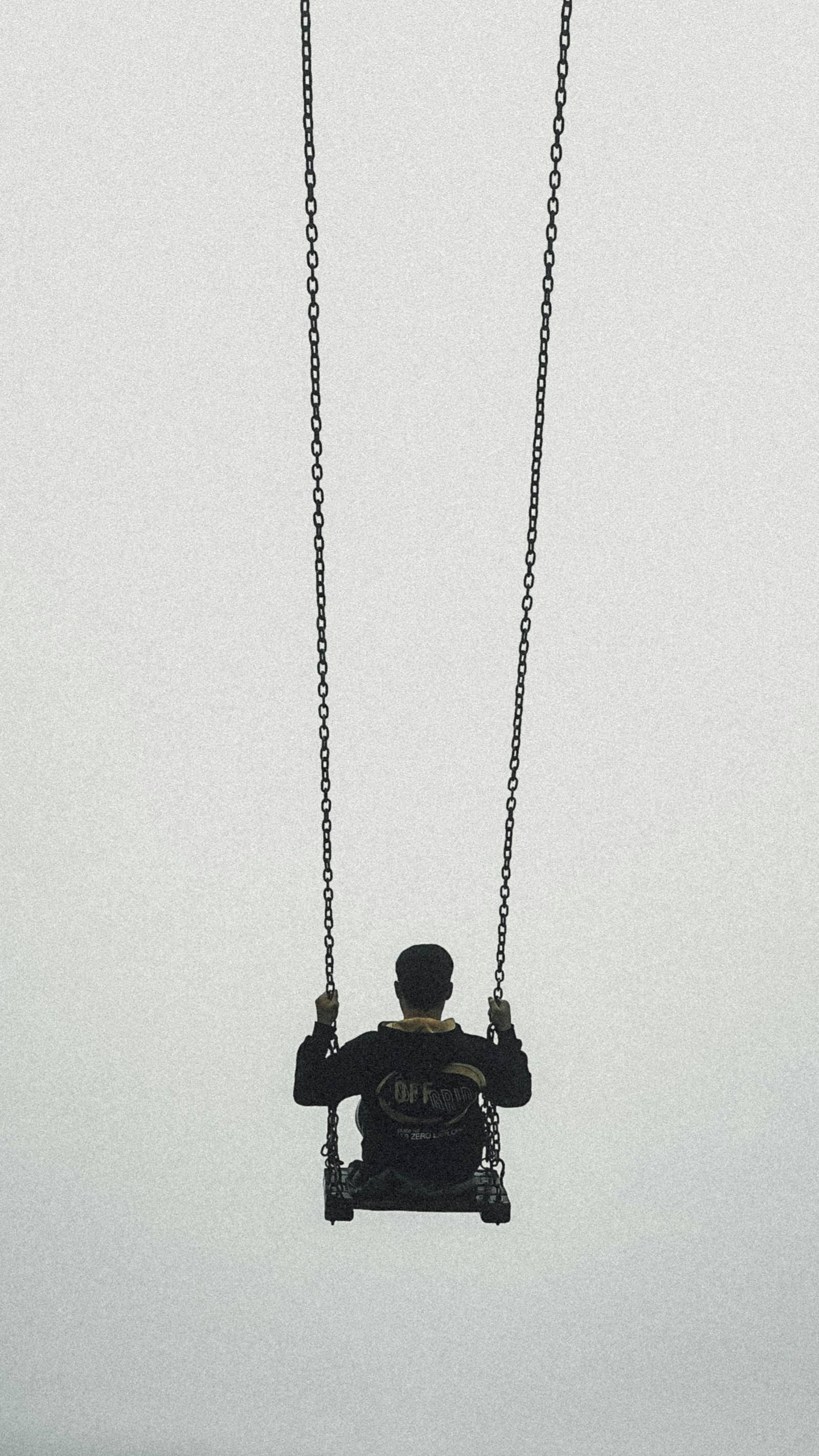 Free A man in dark clothing swings alone against a misty sky in Kümbet, Türkiye. Stock Photo