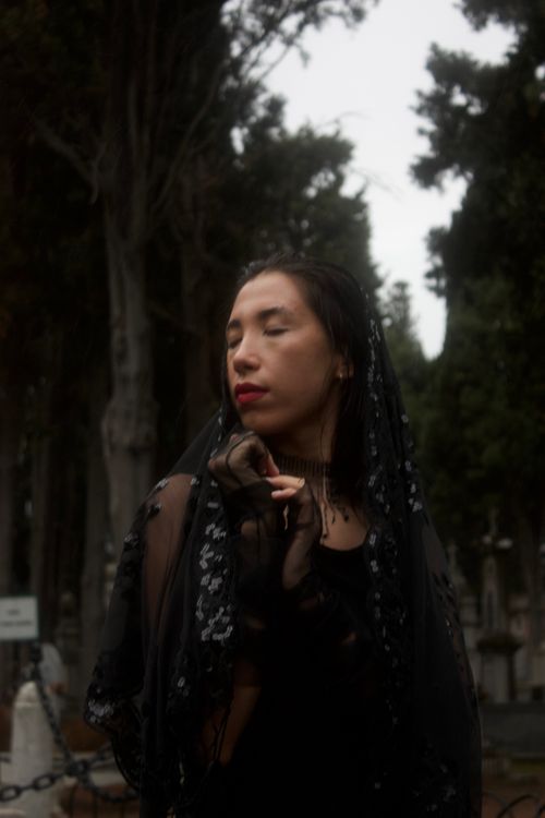 Free Portrait of a woman in mourning attire standing in a mysterious cemetery. Stock Photo