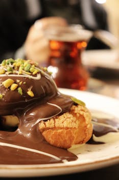 Indulge in a decadent profiterole topped with rich chocolate sauce and pistachios.