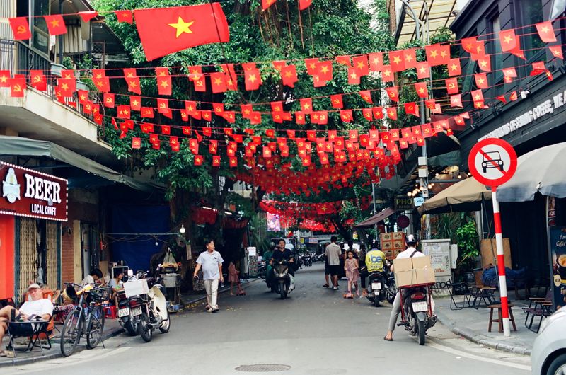 A Hanoi street hung with Vietnamese flags, busy with people and motorbikes