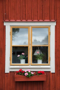 Vintage wooden house facade with charming window and vibrant potted flowers.