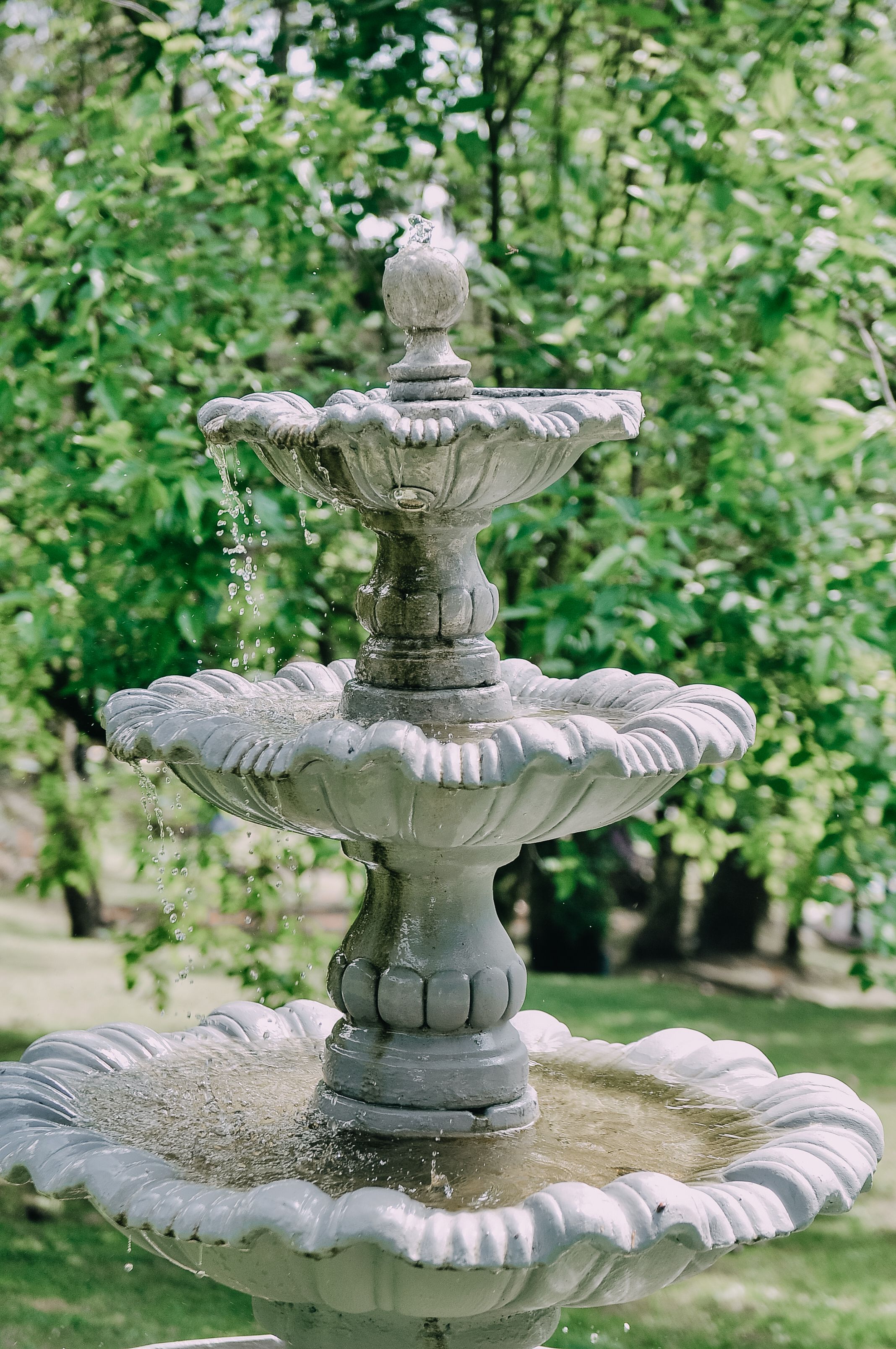Fonte de pedra de três níveis em um jardim verde