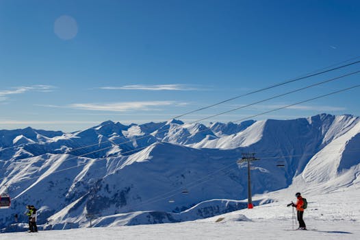Breathtaking view of skiers and snow-covered peaks in Gudauri, Georgia, a popular winter sports destination.