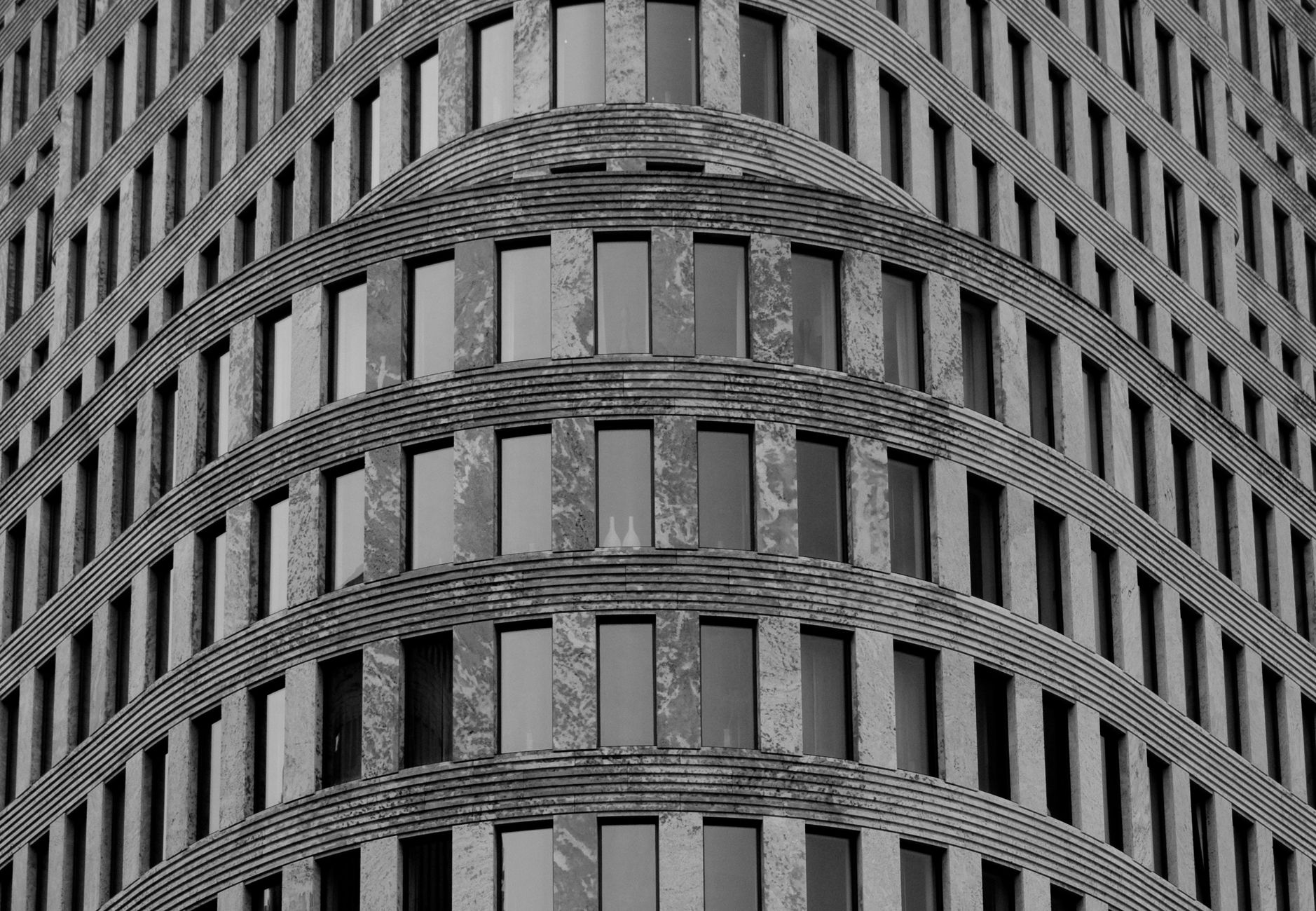 Black and white photo of a modern curved building facade in Berlin, showcasing architectural design.