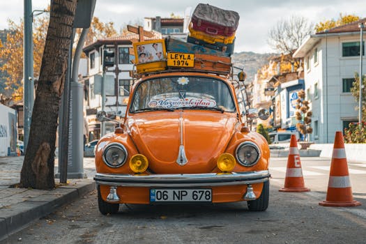 Vibrant orange Volkswagen Beetle with luggage, parked on an autumn street in Afyonkarahisar, Türkiye.