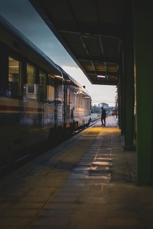 Free A lone passenger waiting by a train at dusk in Eskişehir station, capturing a timeless travel moment. Stock Photo