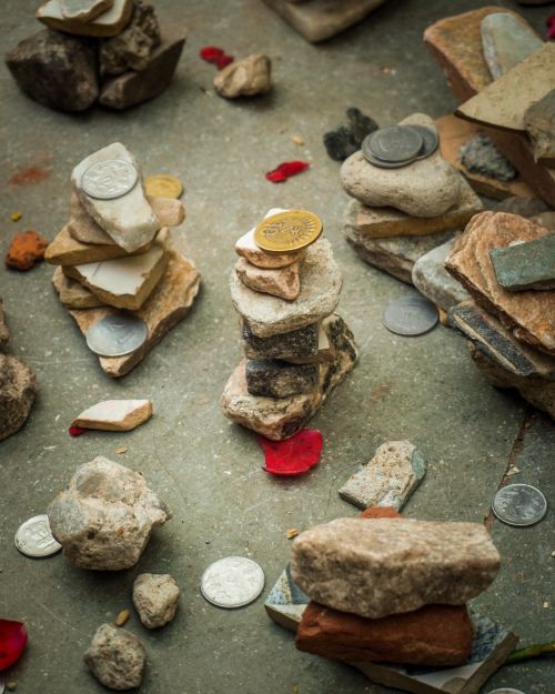 Free Stacked stones and coins on a textured surface with scattered petals, creating a natural yet artistic arrangement. Stock Photo
