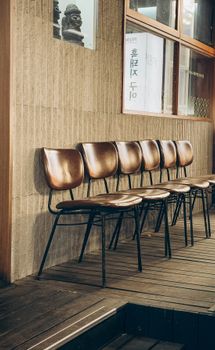Vintage brown chairs lined up against a textured wall in Seoul, South Korea. Urban street atmosphere.