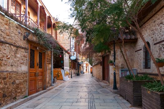 Picturesque view of a narrow street in a historic Mediterranean town, lined with stone buildings and lush greenery.
