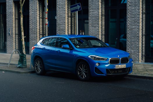 A vibrant blue SUV is parked against an urban brick wall, showcasing a sleek and modern design.