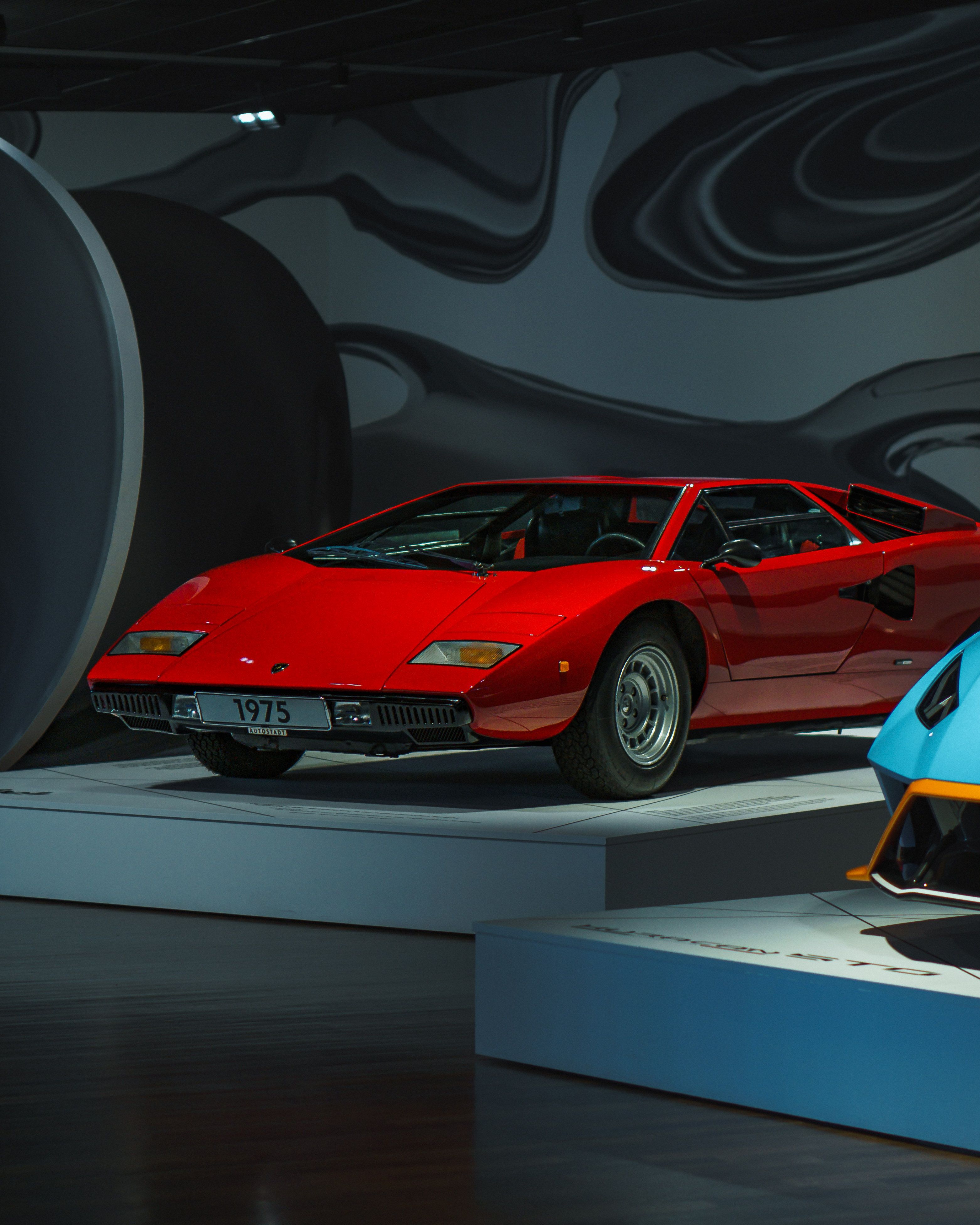 A striking red vintage sports car on display at a modern museum exhibit, showcasing automotive history.