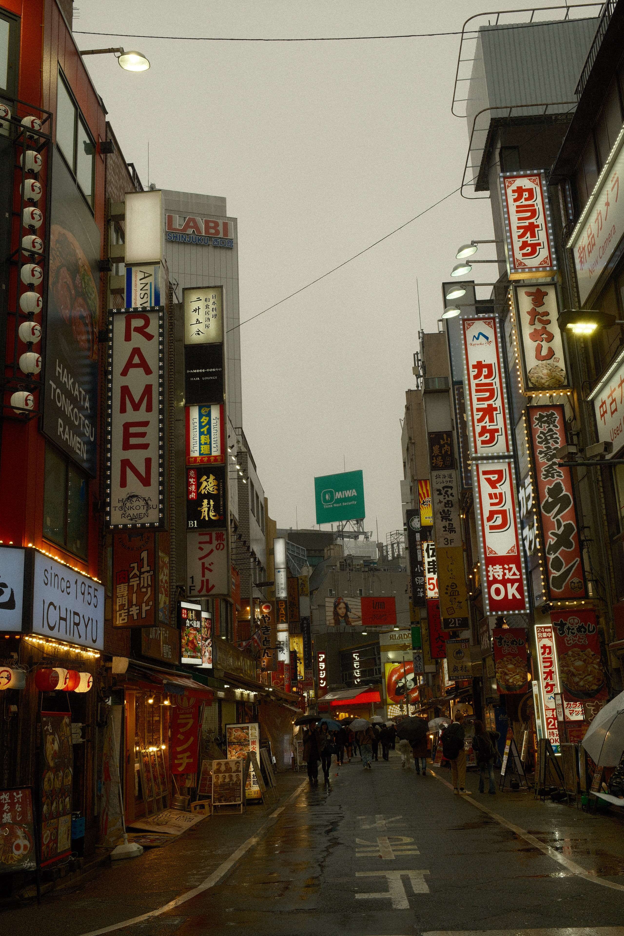 Vibrant Tokyo street with neon signs and people, showcasing urban life.