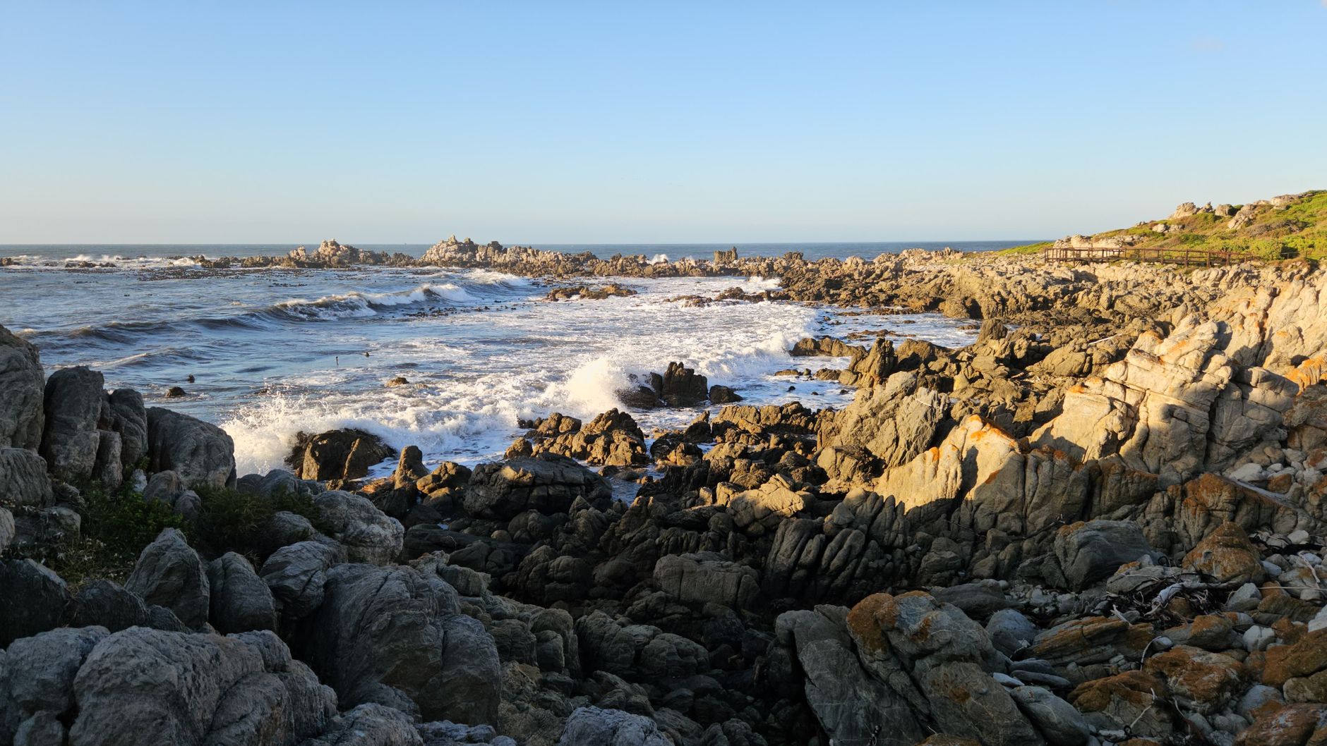 Stunning view of a rocky coastline in South Africa with waves crashing against the shore.