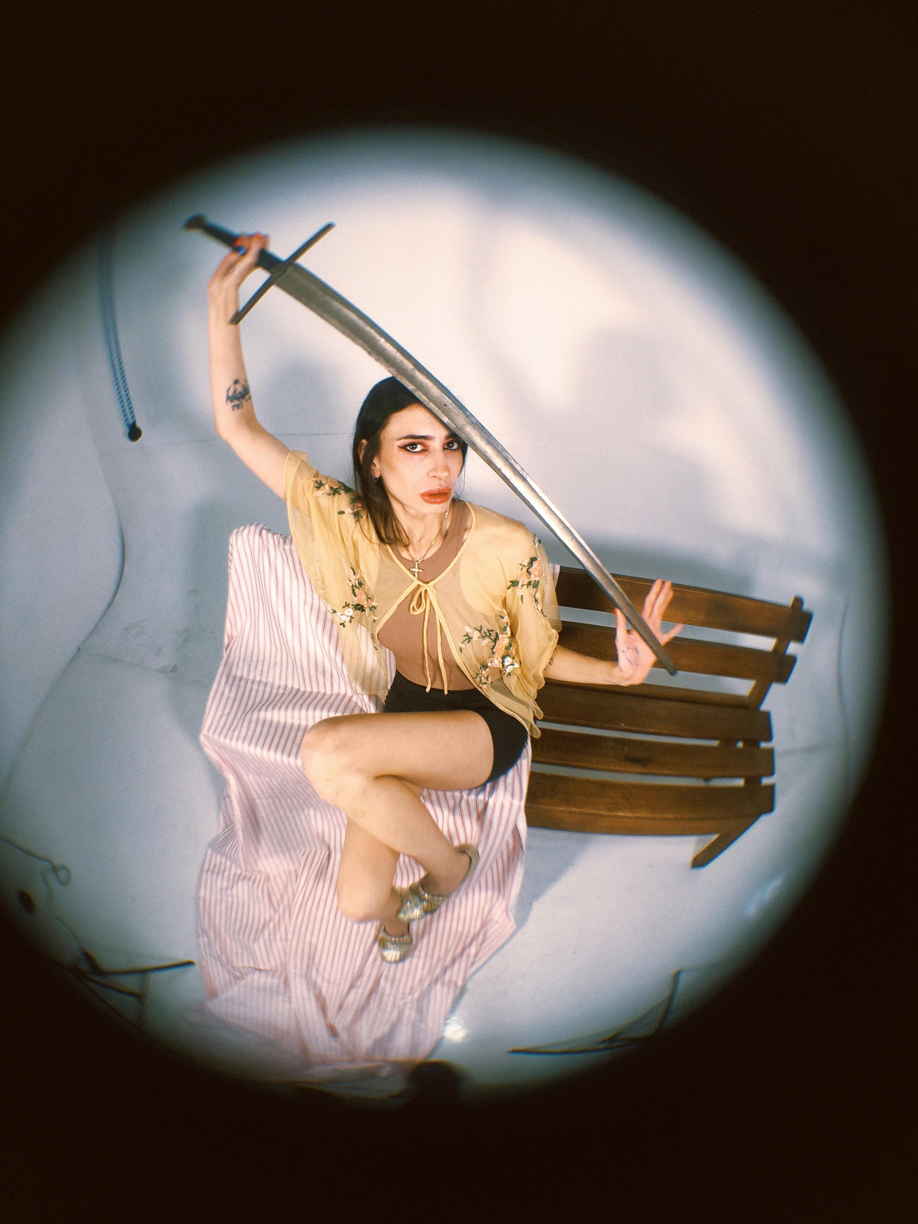Dramatic fisheye portrait of a woman holding a sword, conveying strength.