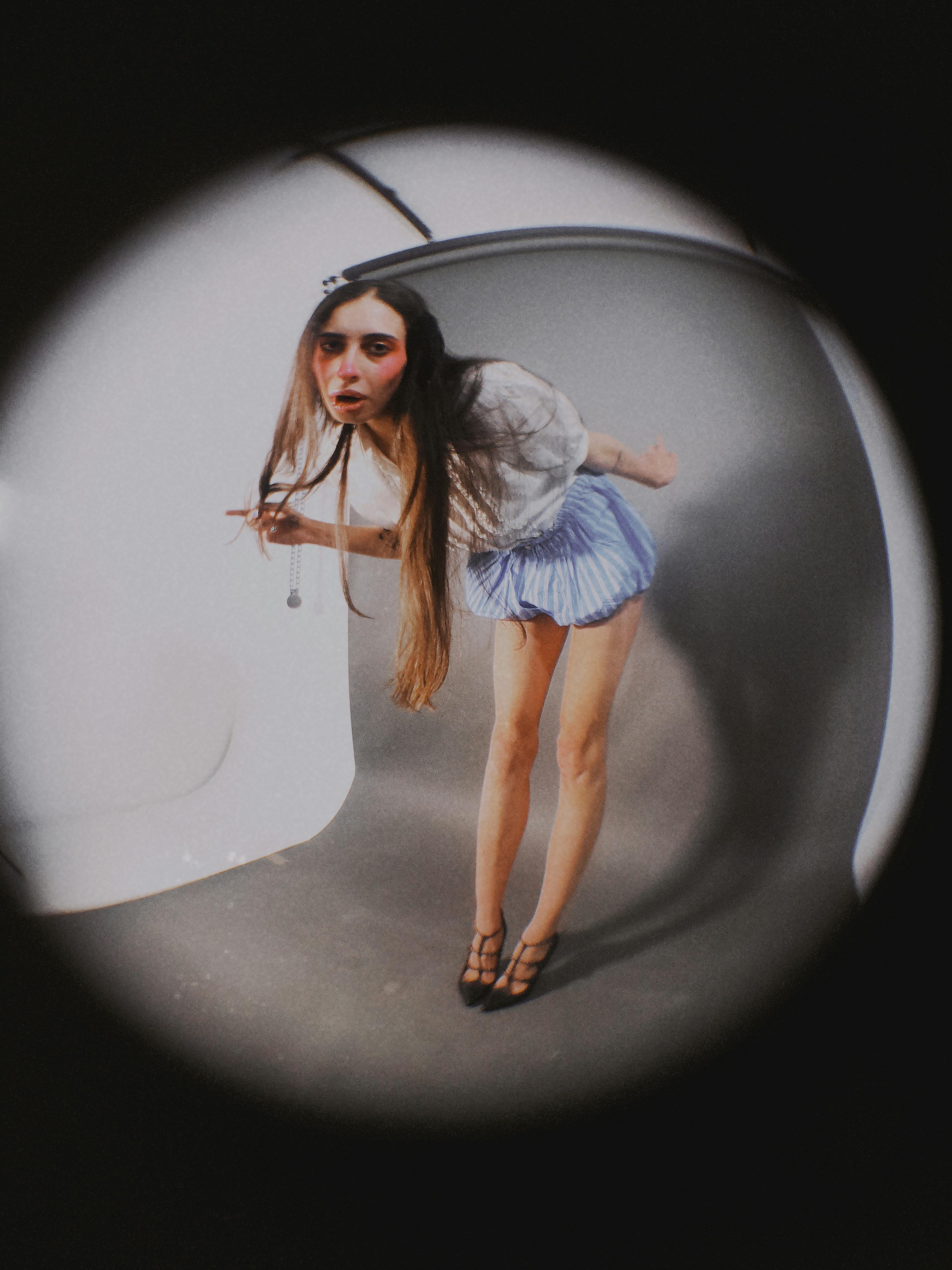 Creative fish-eye portrait of a woman in a studio setting, conveying a unique perspective.