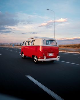 Red vintage Volkswagen van driving on a highway in Ankara, Türkiye during sunset.