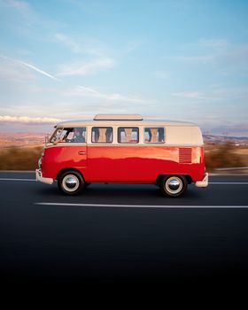 Classic red Volkswagen bus driving on a highway in Ankara under a clear blue sky.