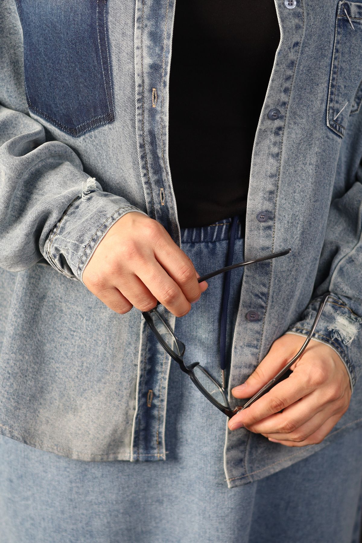 Person holding eyeglasses in casual daily wear