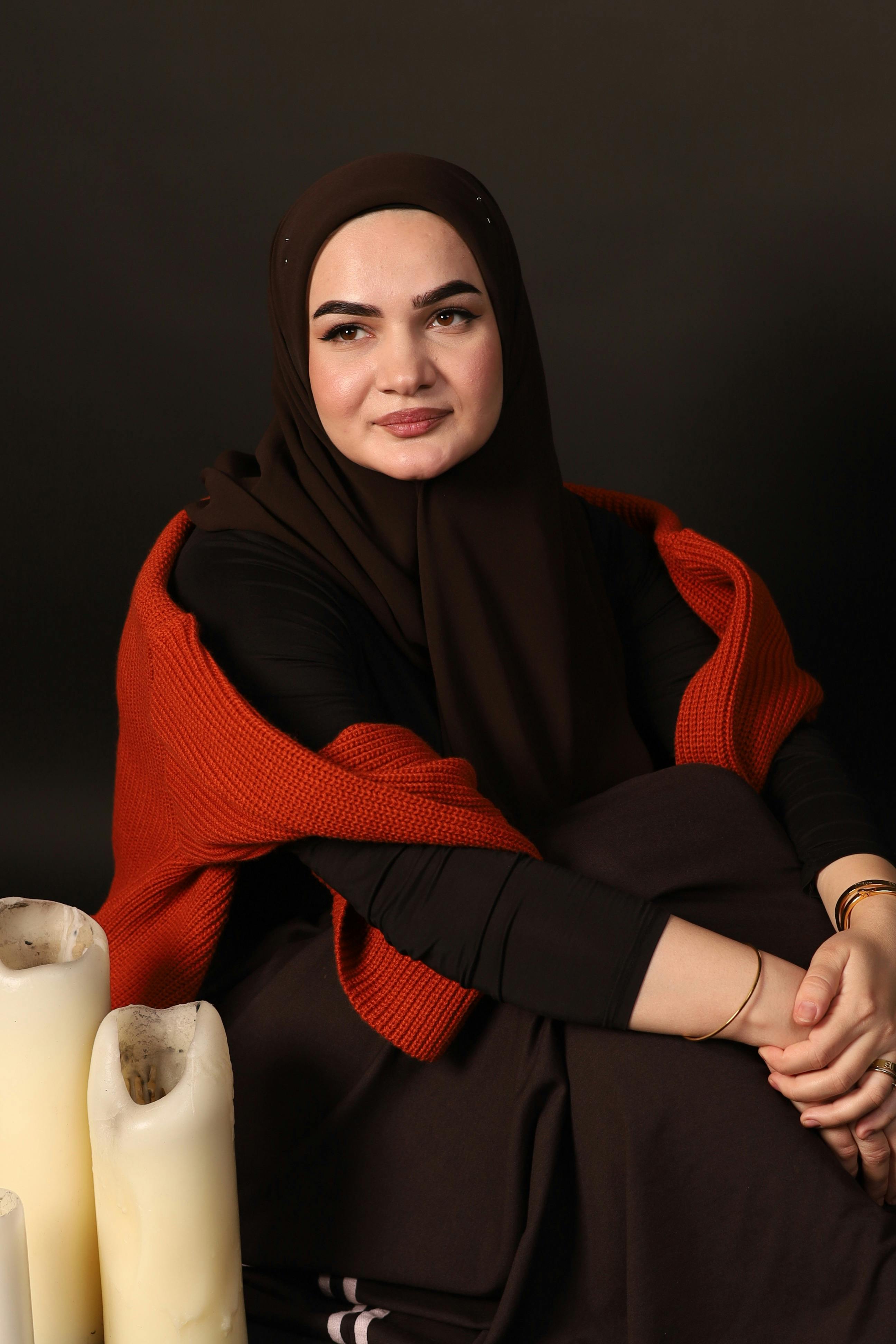 A serene portrait of a woman in a hijab with candles, evoking peacefulness.