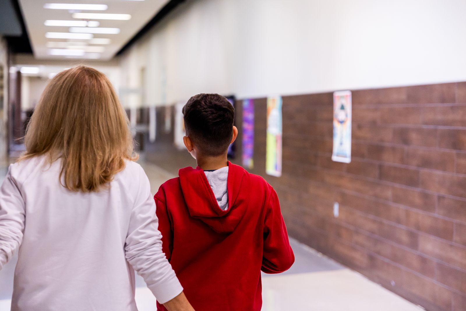 Teacher and student walking together in a school hallway