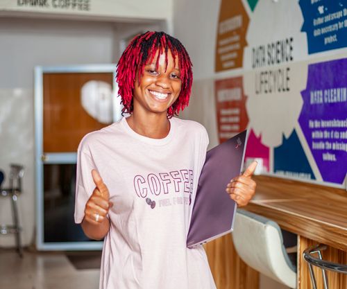Free Cheerful woman with a laptop giving thumbs up in a modern coffee shop interior. Stock Photo