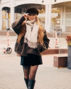 Stylish woman in urban setting wearing a scarf, hat, and boots, perfect for fall fashion inspiration.