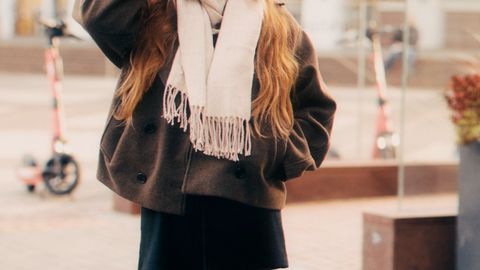 Stylish woman in urban setting wearing a scarf, hat, and boots, perfect for fall fashion inspiration.