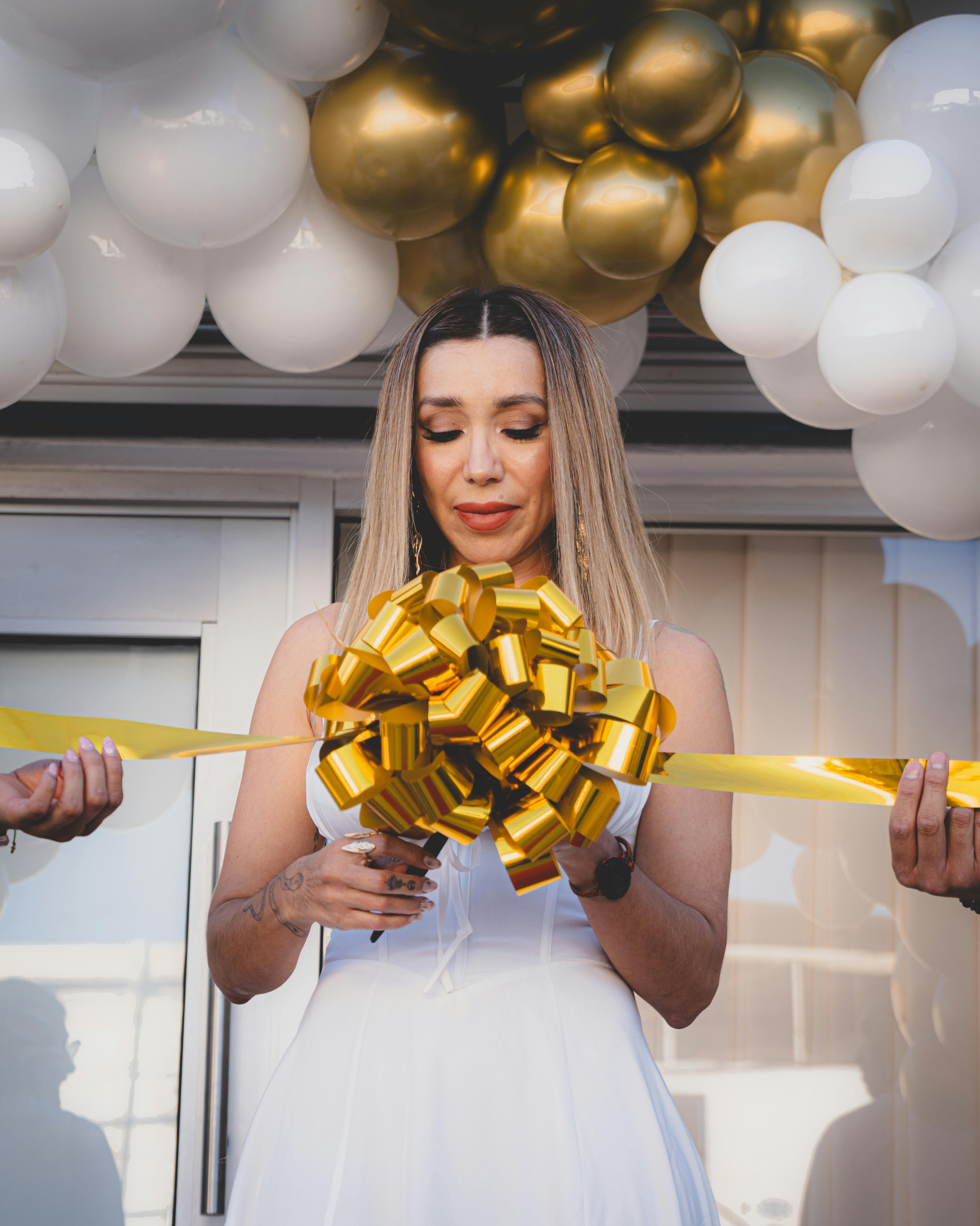 Elegant ribbon cutting ceremony with gold and white balloon decor.