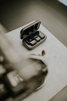 Close-up of a wireless lavalier microphone set in a charging case on a desk.