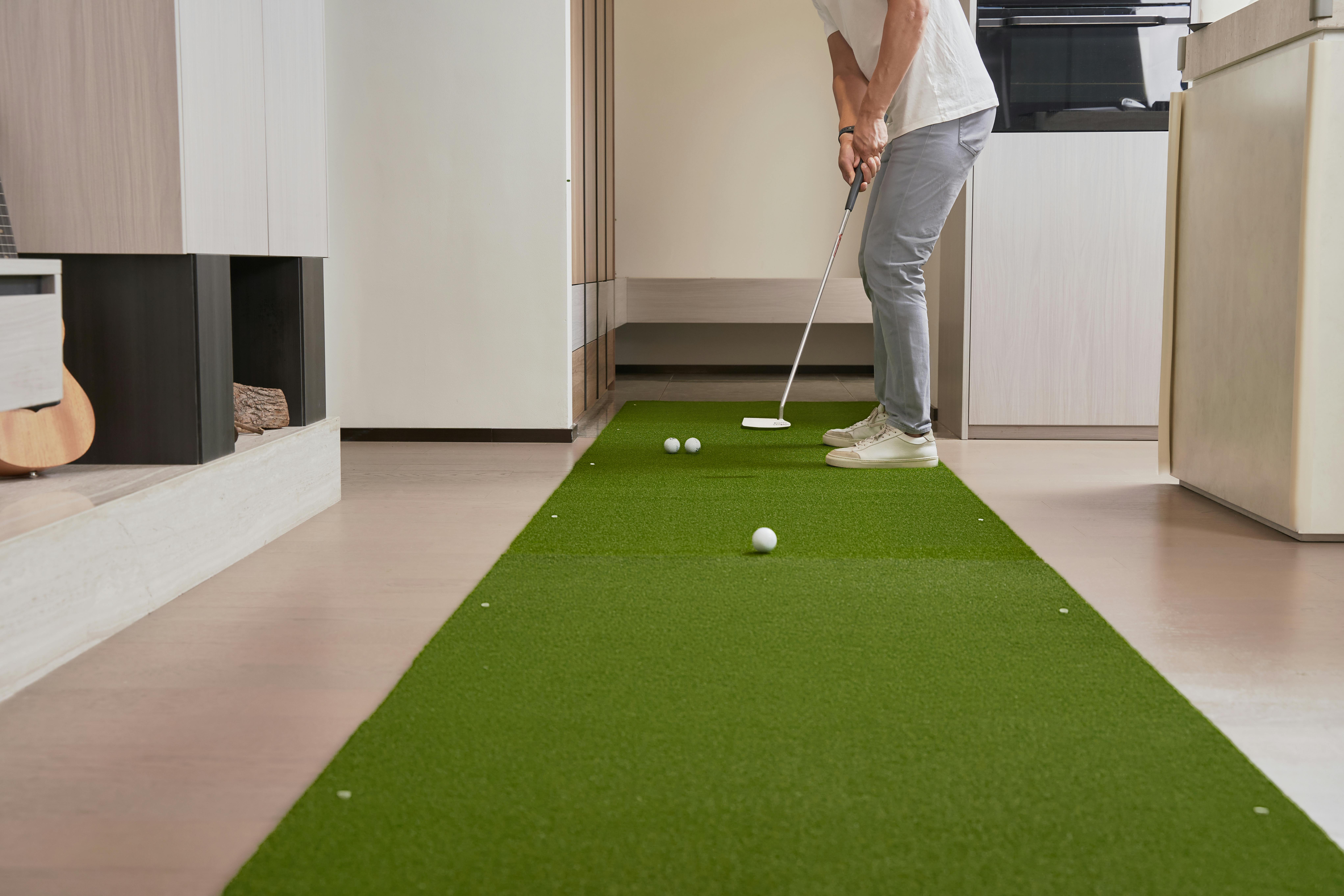 Man practicing golf putts on an indoor artificial turf mat.