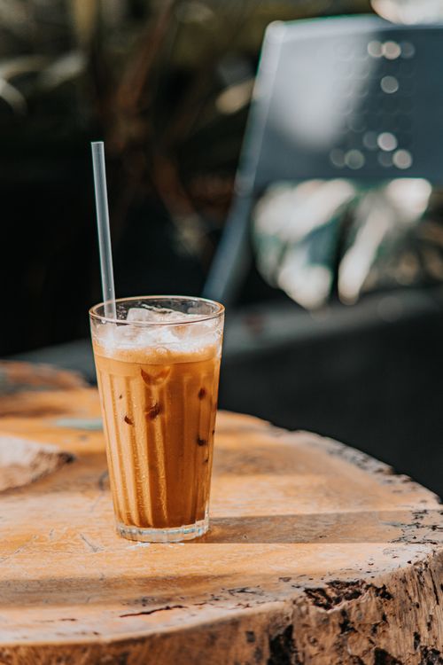Free Chilled iced coffee glass on a wooden table captures a relaxing outdoor moment. Stock Photo