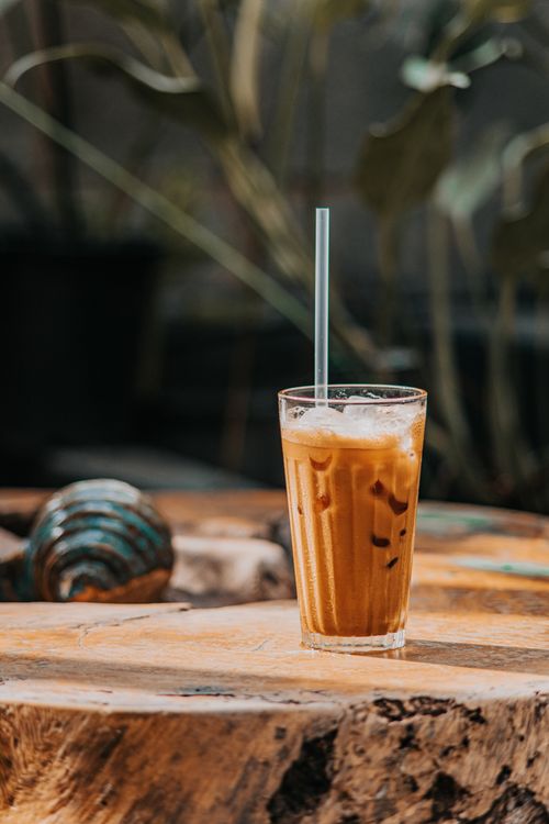 Free Cold iced coffee with straw on a rustic wooden table outdoors, perfect for summer relaxation. Stock Photo