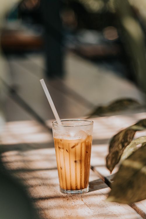 Free A glass of iced coffee on an outdoor table in sunlight, inviting relaxation and refreshment. Stock Photo