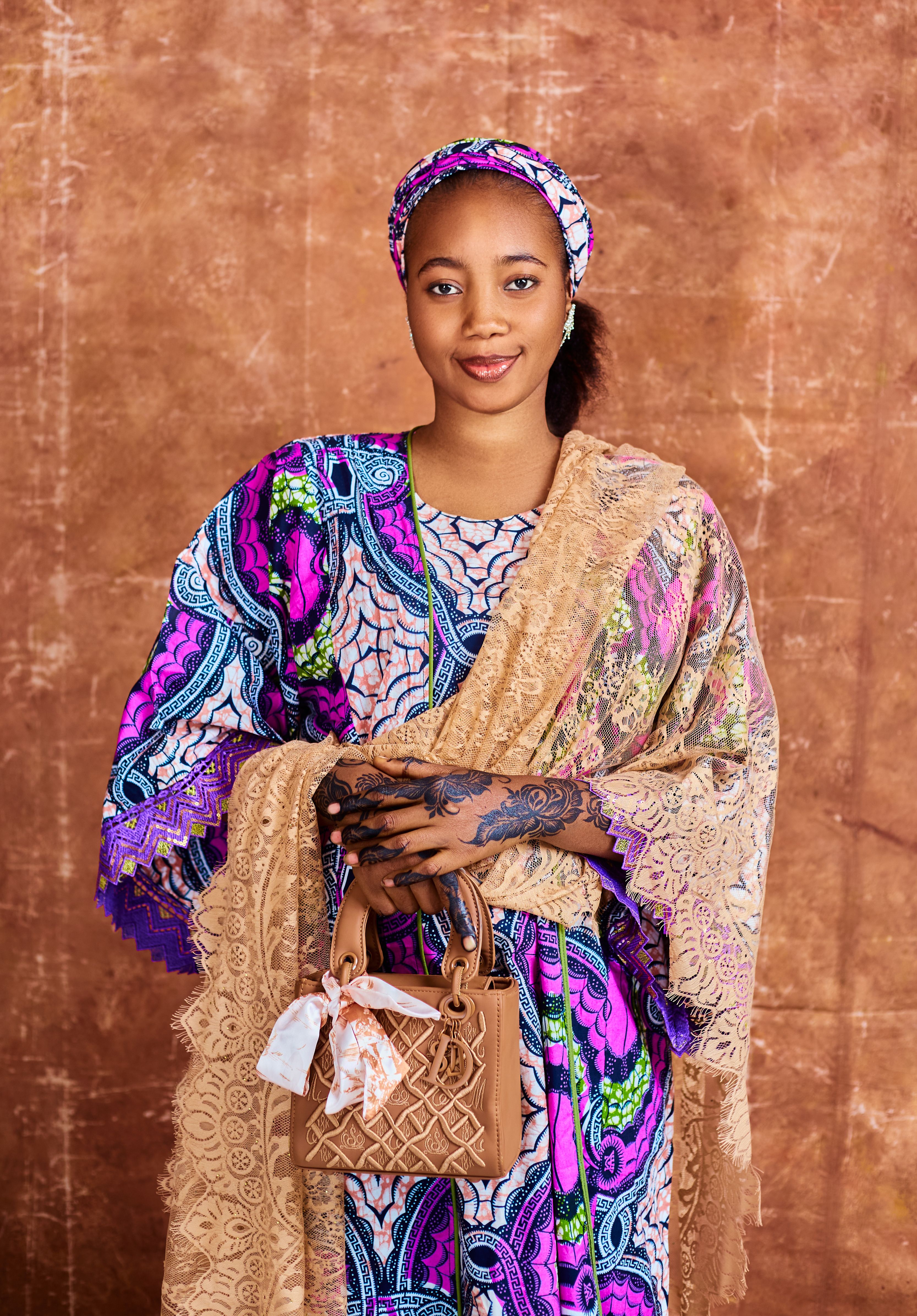 Young woman in vibrant traditional African attire holding a stylish handbag.